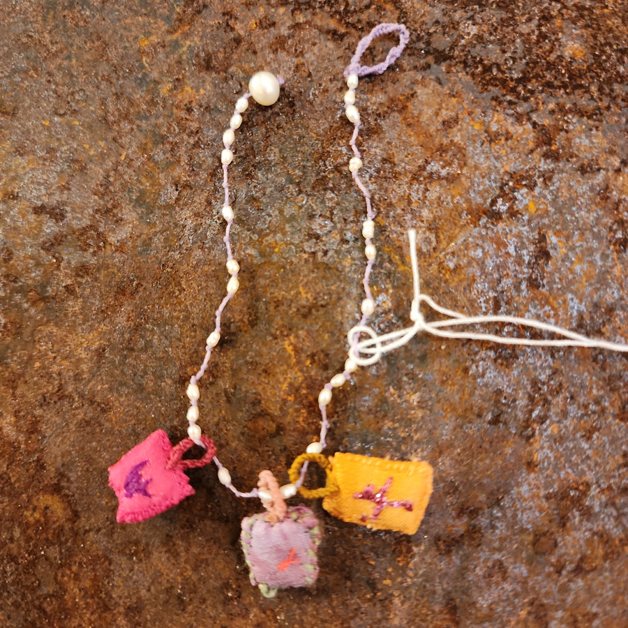 Embroidered silk charm bracelet on a string of semi precious stones by Antonia Rossi